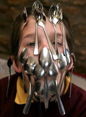 Boy balancing 16 spoons on his face